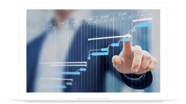A person in a suit points at a digital Gantt chart displayed on a screen, indicating project planning or scheduling.
